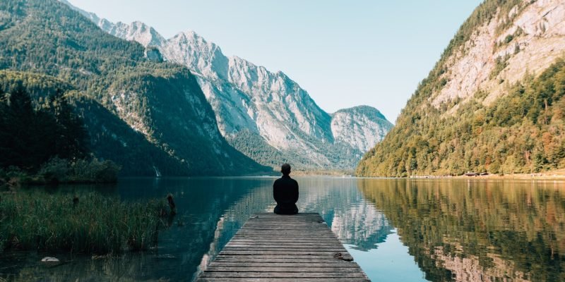 man sitting on gray dock